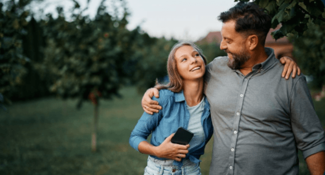 Happy couple using phone outdoors